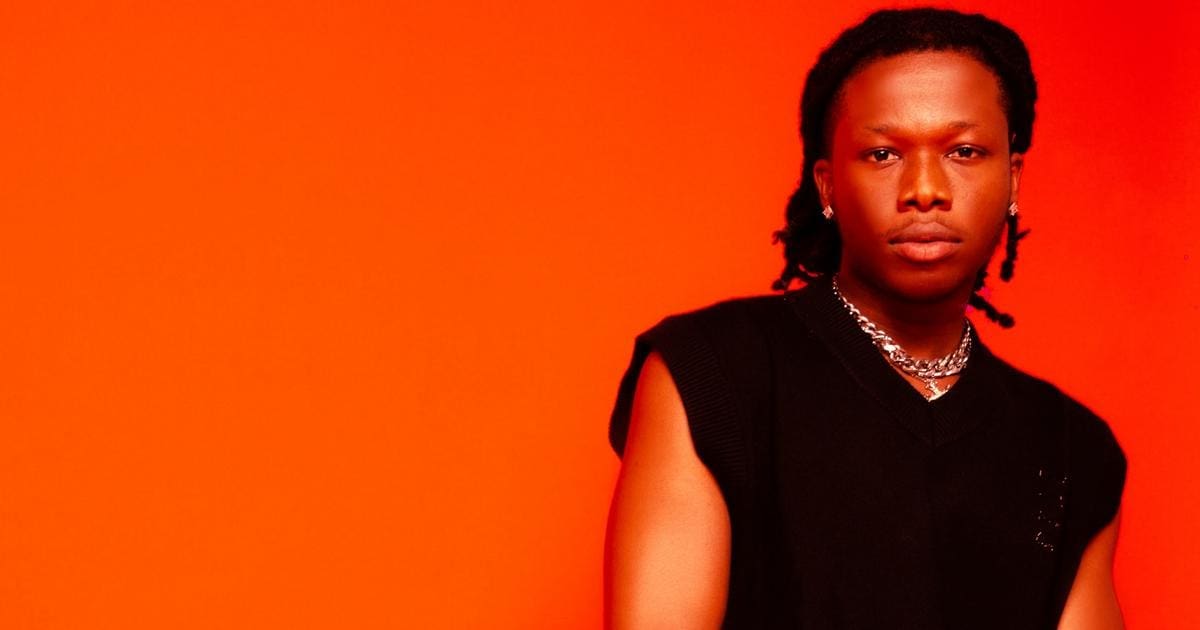 0sektkpTURBXy8xMjFmY2E1YzU1YjdhYjY1NDg3NzM4MjNlYjY2YTNjNS5qcGeSlQPNA5zNBC_NCZTNBWGTBc0EsM0Cdg.jpeg Person with braided black hair, wearing a sleeveless black shirt and silver chain necklace, standing against a solid orange background, looking as though they're about to drop their debut single.