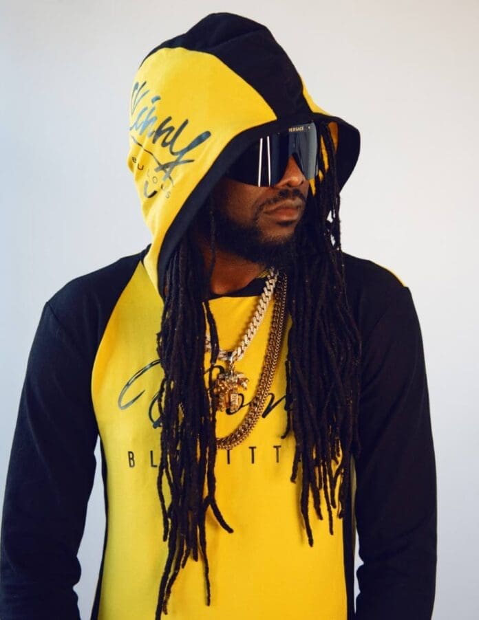 22447370.jpg A person wearing a yellow and black hoodie, dark sunglasses, and multiple gold chains looks to the side, reminiscent of Skinny Fabulous promoting his first album on TT Newsday.