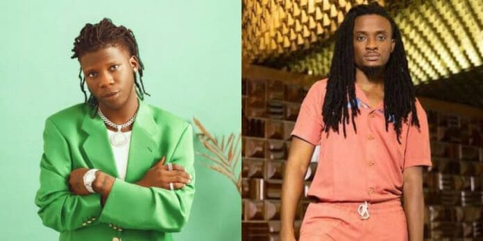 2AB57698-A7E6-4B5A-A261-53E65E7BABA1.jpg Two individuals stand in separate frames. The left one is in front of a light green backdrop, wearing a green suit and jewelry. The right one, evoking Seyi Vibez's vibrant style, is in a rust-colored setting, wearing a pink outfit with dreadlocks.