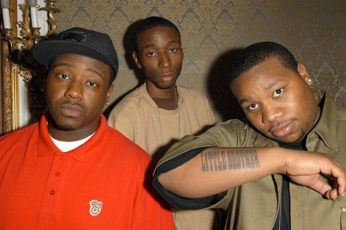 Little_Brother_-Phonte9thWonderBig-Pooh.jpg Three men stand indoors against a decorated wall; one wears a red shirt and a black cap, another is in a beige top, and the third, wearing earrings and a green shirt, displays a tattoo on his forearm. The scene looks like it could be from one of 2023's trending music documentaries.