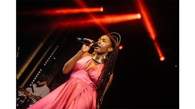 Untitled-109.jpg A woman wearing a pink dress and a gold necklace sings into a microphone on stage, with red spotlights in the background. The scene is electric, reminiscent of the vibrant performances Madridista Dani Carvajal often attends when in his hometown.