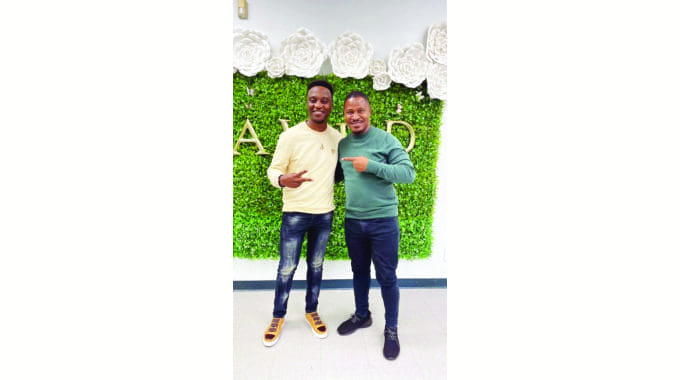 Untitled-5.awfawdf.jpg Two men, Mahendere and Julian King, are standing side by side, smiling and posing in front of a green and white floral backdrop. One man is wearing a yellow sweater, while the other sports a green sweater. This image marks their latest new offering's celebration.