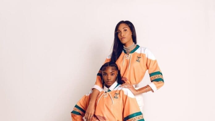 Two women posing for a photo to celebrate the 8-year anniversary of Mizizi, an African diaspora streetwear brand. Two women posing for a photo to celebrate the 8-year anniversary of Mizizi, an African diaspora streetwear brand.