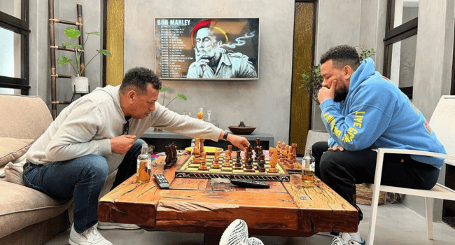 Two men playing chess in a living room while AKA's father shares his thoughts on his son's ongoing murder investigations. Two men playing chess in a living room while AKA's father shares his thoughts on his son's ongoing murder investigations.