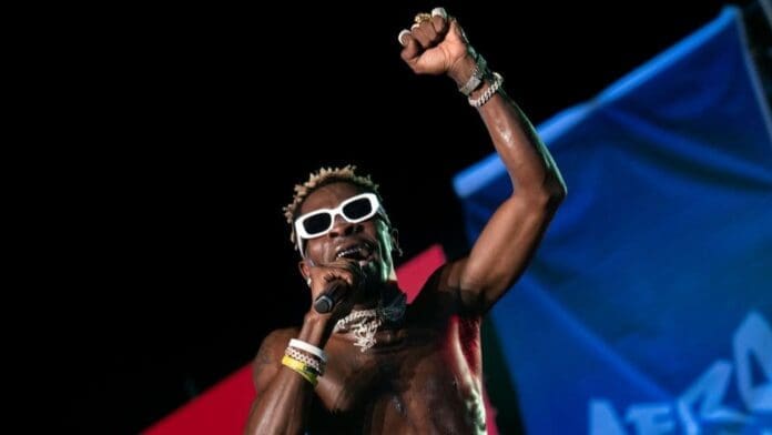 A man in Ghana's shirt and shorts is holding a microphone. A man in Ghana's shirt and shorts is holding a microphone.