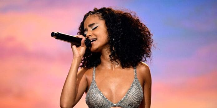 A woman in a silver bikini singing into a microphone is Tyla, the 'Water' singer. A woman in a silver bikini singing into a microphone is Tyla, the 'Water' singer.