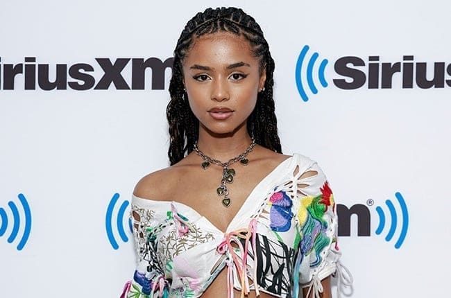 A black woman in a colorful top posing on the red carpet. A black woman in a colorful top posing on the red carpet.