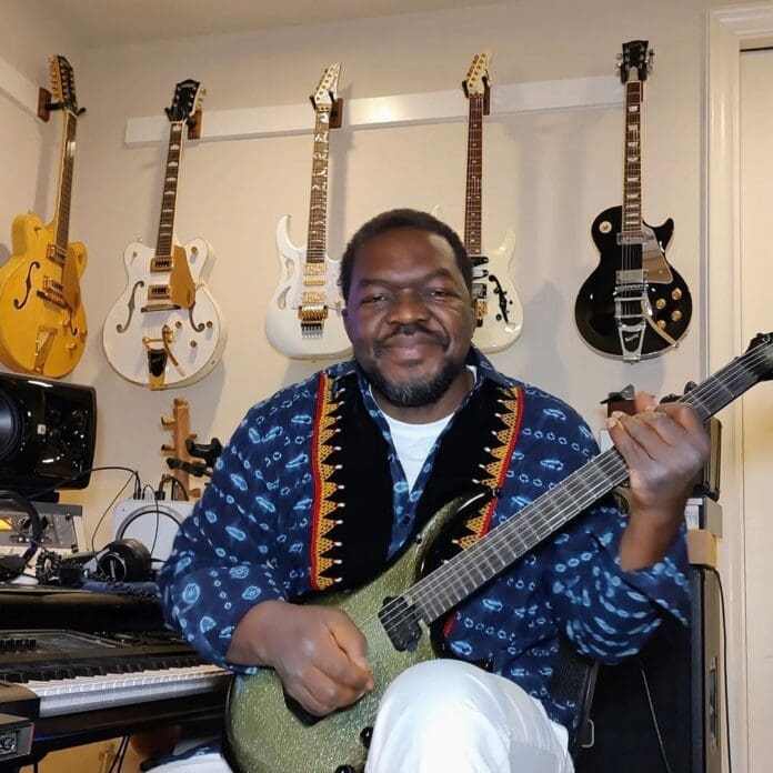 A Cameroonian artist holding a guitar in front of a wall of guitars, galvanizing Moghamo culture. A Cameroonian artist holding a guitar in front of a wall of guitars, galvanizing Moghamo culture.