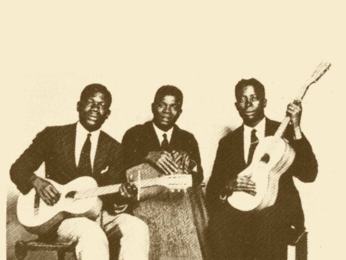 A black and white photo of three men playing guitars in the dizzying destiny of palm wine music. A black and white photo of three men playing guitars in the dizzying destiny of palm wine music.