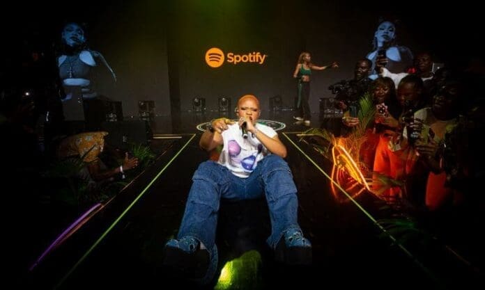 A man is sitting on the floor in front of a crowd of people during an Afrobeats celebration in Lagos. A man is sitting on the floor in front of a crowd of people during an Afrobeats celebration in Lagos.