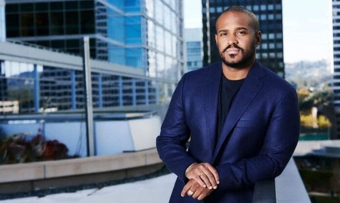 A man in a blue suit posing in front of a building streaming Spotify. A man in a blue suit posing in front of a building streaming Spotify.