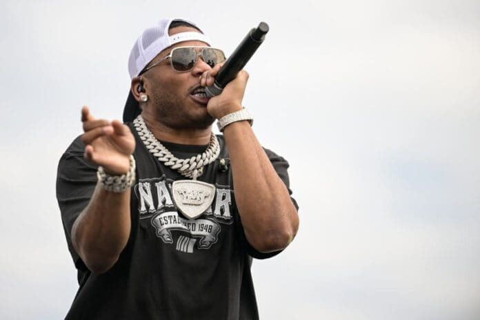 A man wearing sunglasses and a hat is singing into a microphone in the vibrant music scene of St. Louis, featured by SPIN magazine. A man wearing sunglasses and a hat is singing into a microphone in the vibrant music scene of St. Louis, featured by SPIN magazine.