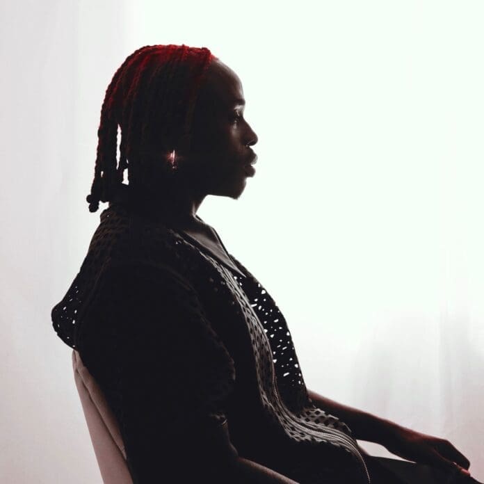 A soul-stirring silhouette of a woman with fiery red hair sitting in OH MY, a captivating throne-like chair, reminiscent of Fireboy DML's passionate energy. A soul-stirring silhouette of a woman with fiery red hair sitting in OH MY, a captivating throne-like chair, reminiscent of Fireboy DML's passionate energy.