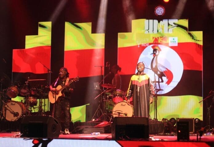 A group of people on stage showcasing African genres with an African flag as a backdrop. A group of people on stage showcasing African genres with an African flag as a backdrop.