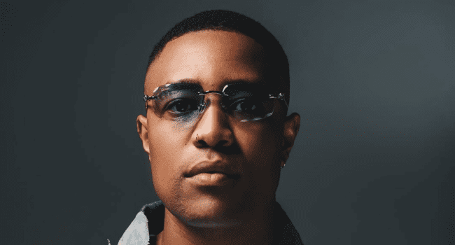 DJ-Speedsta-5.png A person wearing sunglasses looks directly at the camera against a dark background, exuding the cool confidence of a Hip Hop artist.