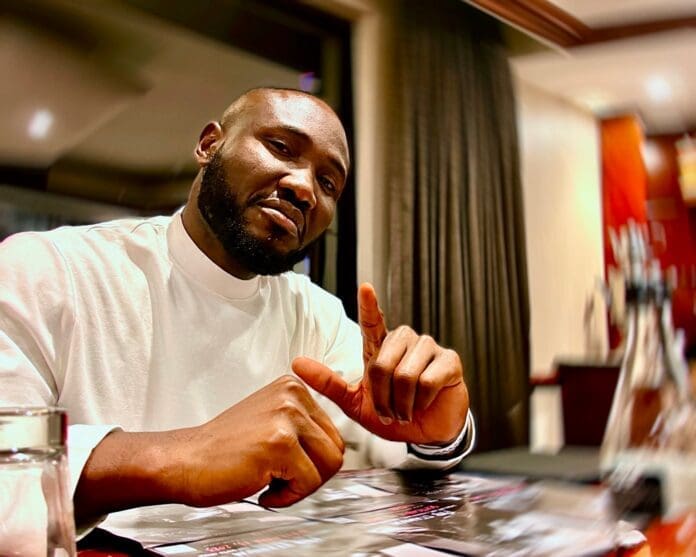 Geobek-.jpg A man in a white shirt sits at a table indoors, gesturing with one finger raised while looking at the camera, reflecting Geobek’s global ambitions.