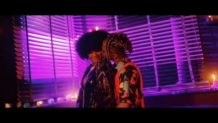 Two people stand close together in a dimly lit room with purple lighting, candles, and blinds in the background—capturing the mood of CKay’s Official Music Video for Love Nwantiti Remix.