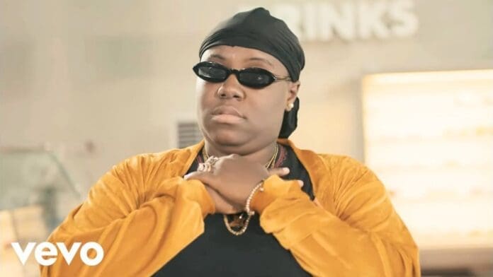 A person wearing dark sunglasses, a black headscarf, and gold jewelry stands with their hands crossed on their chest. The "Vevo" logo and "Teni Case Official Video" text appear in the bottom left corner.