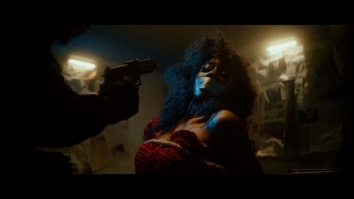 In a scene reminiscent of "Running (To You)" by Chiké and Simi, a woman with tape over her mouth sits tied to a chair while a person points a gun at her in a dimly lit room, scattered with papers on the wall.