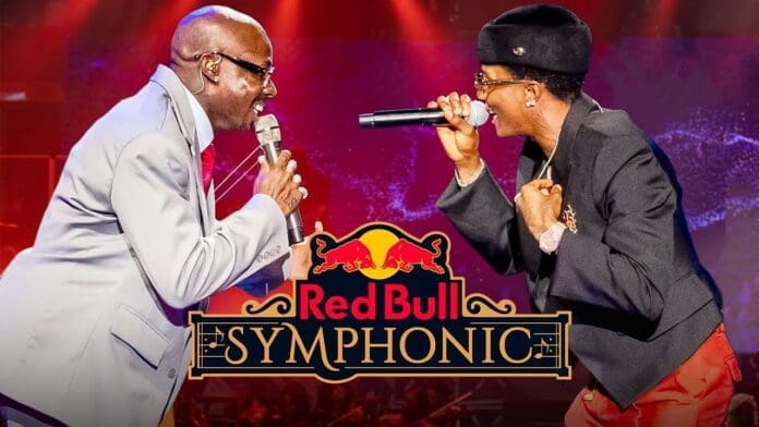 Two performers, reminiscent of WizKid and Asake, sing passionately on stage facing each other, both holding microphones, with the Red Bull Symphonic logo prominently displayed in the foreground.