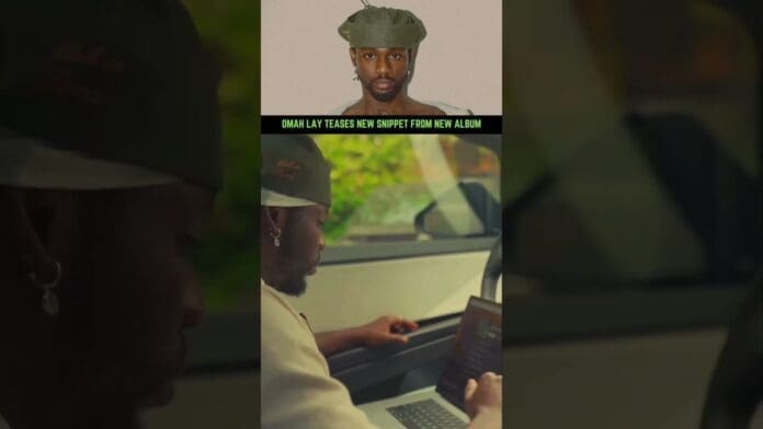 A man sits in a car working on a laptop; above is a portrait of Omah Lay in a green cap with text that reads, "Omah Lay teases new afrobeats snippet from new album, CLARITY OF MIND.