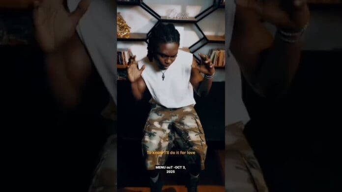 A person in a white sleeveless shirt and camouflage shorts sits before shelves, with captions overlaid promoting Bayanni's new music and a menu release on OCT 3 2025.