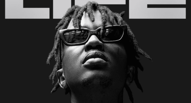 A person with short dreadlocks and sunglasses looks upward against a black background, with the word "LIFE" partially visible at the top—a scene echoing artists like Emtee facing December gig pressure.