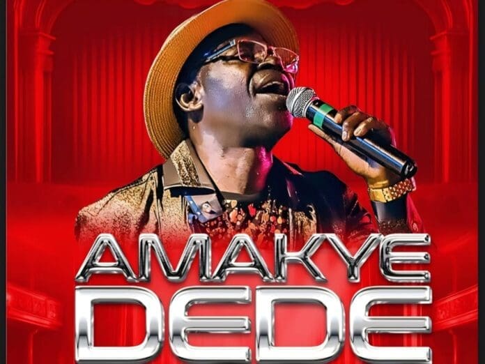 A man in a hat and glasses sings into a microphone on stage, with the text "AMAKYE DEDE" in bold letters at the bottom, celebrating Amakye Dede’s legacy at the Amapiano Invasion event.