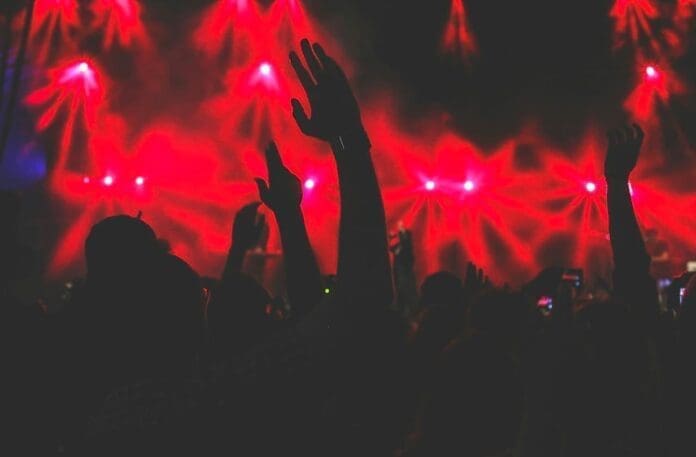 Crowd with raised hands silhouetted against bright red stage lights captures the energy of Nigeria live music and unforgettable concert experiences.