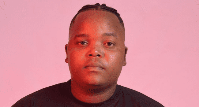 A person with short braided hair and a neutral expression faces the camera against a pink background, wearing a black shirt—capturing the vibe of Intaba Yase Dubai's new album, "From Me To You.