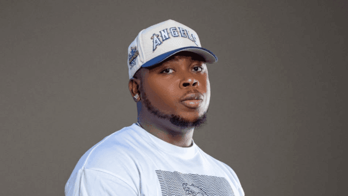 A man wearing a white Raploard graphic t-shirt and a white baseball cap stands against a plain gray background.