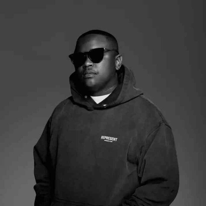 A person wearing sunglasses and a dark hoodie with "REPRESENT" printed on it stands against a plain, dark background, channeling the cool vibe of a DJ mix by Stanky DeeJay.