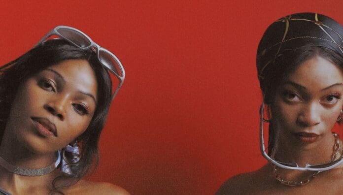 Two women pose against a solid red background, representing leading Female Amapiano Artists of 2025. One wears sunglasses on her head and a necklace; the other features a black headscarf with sunglasses around her neck.