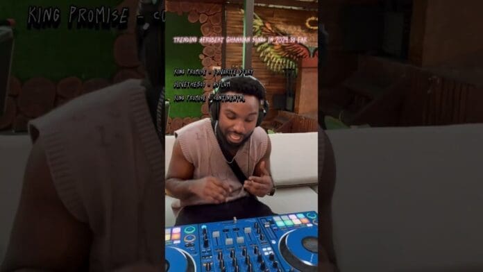 A man sits at a DJ controller, wearing headphones and gesturing with his hands. Text above showcases Trending Songs Ghana and top Ghanaian Afrobeat Songs from King Promise in 2024.