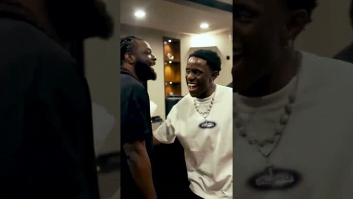 Two men, Terry G and Victony, stand indoors facing each other and smiling in a warmly lit room with cabinets and ceiling lights visible in the background.