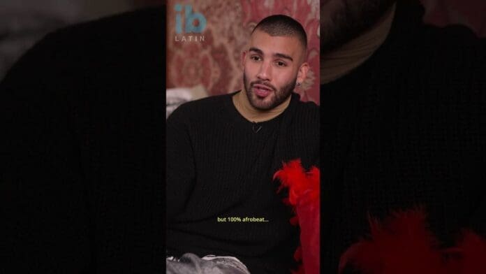 A man sits on a bed, listening to new music by Manuel Turizo.