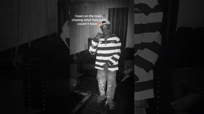 A man wearing sunglasses, a striped shirt, and ripped jeans stands indoors; text above reads, "I been on the road... chasing what they said I couldn't have." This trending look captures the vibe of determination and hustle.