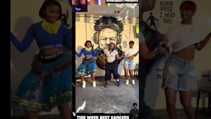 Three people energetically perform an amapiano dance challenge indoors, wearing colorful outfits with vibrant murals in the background. Text overlays read “THIS WEEK BEST DANCERS” and “PLEASE SPEED I NEED THIS.”.