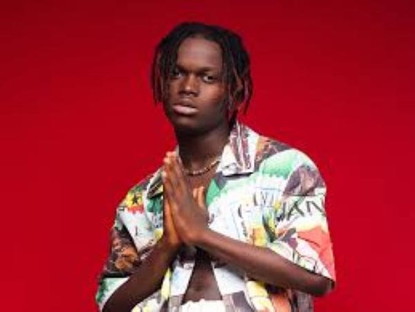 56972901.jpg A young person with medium-length dreadlocks stands in front of a red background, wearing a patterned shirt and holding their hands together in front of their chest, embodying the vibrant Ghanaian Afrobeats style featured on GhanaWeb.