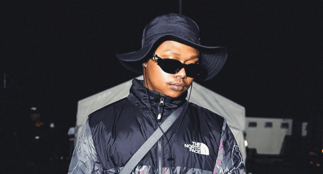 A man wearing sunglasses and a hat, inspired by A-Reece's iconic style and passion for songwriting.