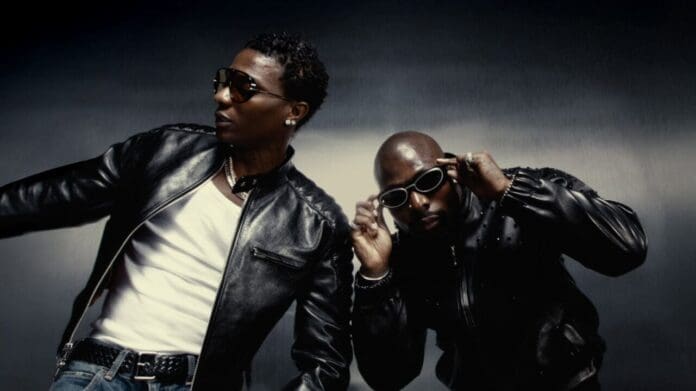 Two men wearing black leather jackets and sunglasses pose against a dark, gradient background, channeling the cool vibes of Wizkid and Asake.