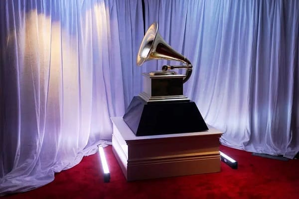 A large Grammy Award trophy displayed on a pedestal with white curtains and red carpet in the background, reminiscent of honors received by Nigerians with most Grammy awards, as featured in The Nation Newspaper.