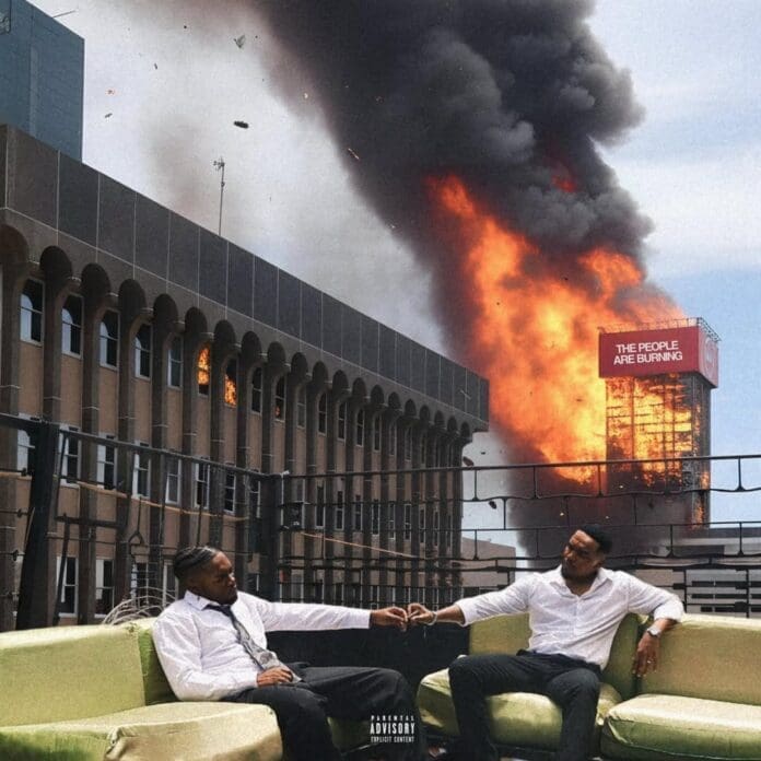 Two men sit calmly on a rooftop patio while a nearby building, seemingly ablaze with the intensity of a Jay Jody and Manu WorldStar collaborative album, burns. A sign on the burning building reads "THE PEOPLE ARE BURNING.