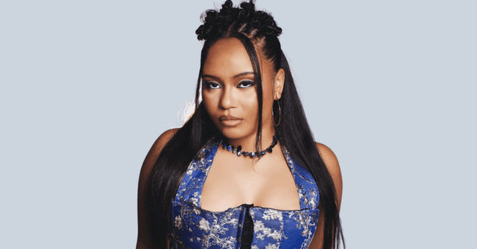 A woman with long dark hair and braids, Ghanaian singer MOLIY—featured on Spotify EQUAL Africa—wears a blue floral-patterned top and a black necklace as she poses against a plain light background.