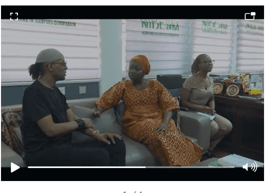 Three people, including Jeffrey Daniel, sit and have a conversation in an office, with plaques and awards displayed on a shelf behind them.