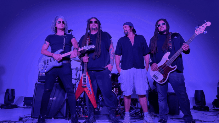 Four men stand in front of musical instruments and amplifiers under a purple glow; three hold electric guitars and wear sunglasses, while one is in casual attire. This is Orange Sky debuting their new single, "Too Many.