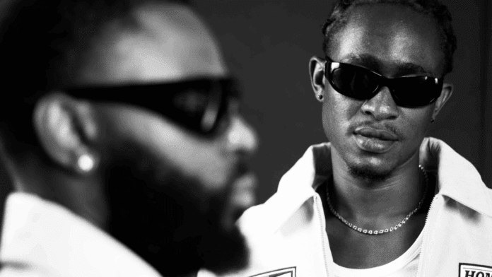 Black and white photo of two men wearing sunglasses; one is in sharp focus facing forward, the other is blurred in the foreground facing sideways—a striking visual for their new single, blending style and Afro-Fusion vibes.