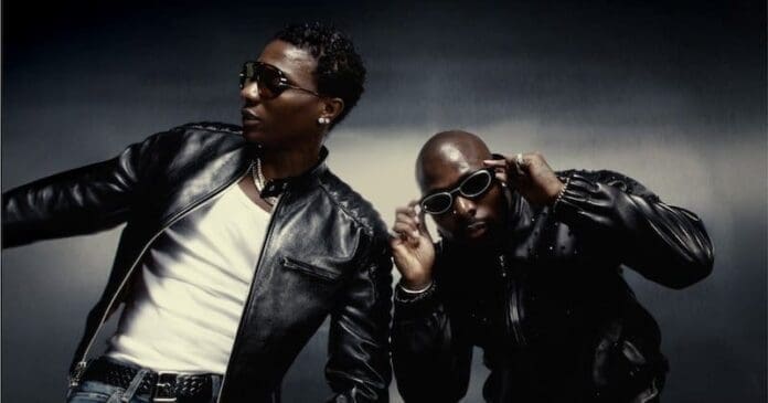 Two men wearing black leather jackets and sunglasses pose against a dark background, channeling Afrobeats flair. One adjusts his glasses like Wizkid, while the other leans slightly to the side.