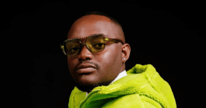 A person wearing yellow-tinted glasses and a bright green fuzzy jacket poses against a black background, channeling amapiano vibes reminiscent of a Soa Mattrix new song.
