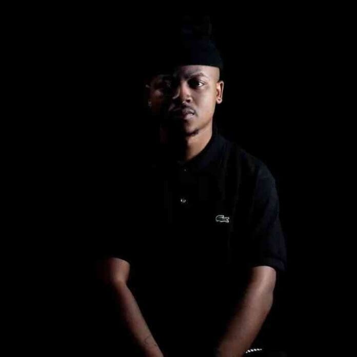 A man wearing a black shirt and hat sits against a dark background, his face partially illuminated by light from the left—capturing the moody vibe of a Jaylokas or Bongza Top Dawg Sessions set.